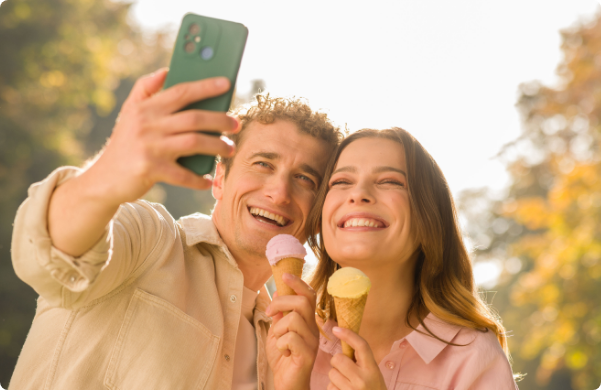 Šťastný pár si pořizuje selfie se zmrzlinou a užívá si slunečný den pod širým nebem.